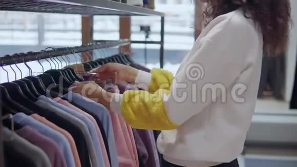 女购物者正在从货架上拿两件衣服进入更衣室视频的预览图