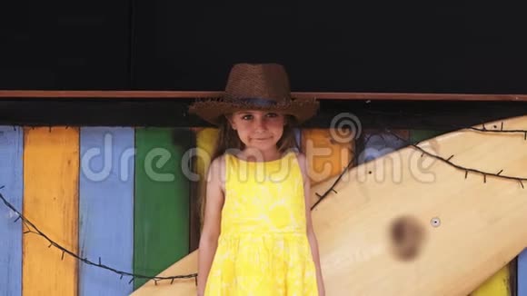 穿着黄色衣服的小美女站在冲浪板旁边视频的预览图