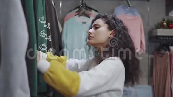 青春期的女孩在商店里看着时髦的运动衫和青春服装视频的预览图