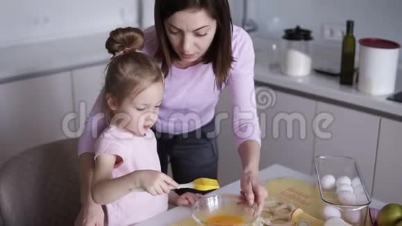 家庭烹饪和人的概念幸福的母亲和她的小女儿在家里厨房用带鞭子的饼干视频的预览图