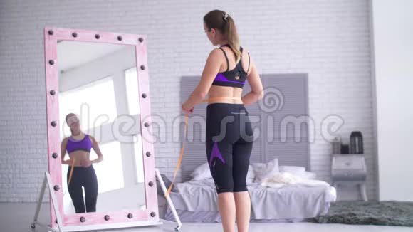 带着卷尺看镜子的运动女人视频的预览图