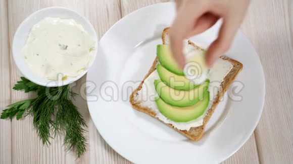 准备健康早餐的女人烤面包奶酪和鳄梨鹌鹑蛋视频的预览图