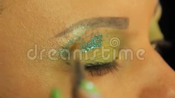 一个拿着刷子的女人眼睛上布满了绿色的阴影多汁的绿色火花视频的预览图