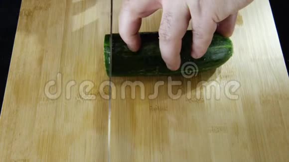 在餐厅的厨房里人的双手慢慢地在木板上切一根新鲜黄瓜股票视频的预览图