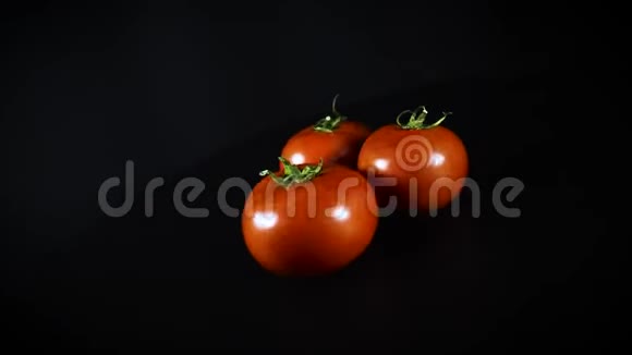 蔬菜三个红色西红柿黑色背景上有绿色的尾巴视频的预览图
