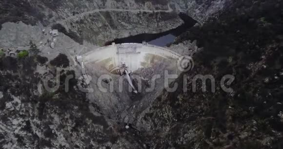 空中拍摄的一个大坝它支撑着一个树林茂密的山塘和一条蜿蜒的道路视频的预览图