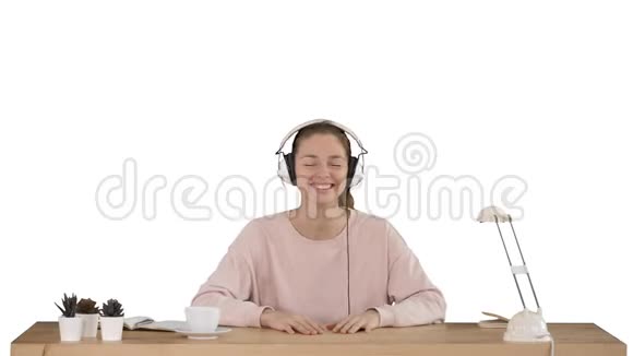 漂亮的女士穿着粉红色套头衫听着耳机里的音乐在白色背景上微笑着对着相机视频的预览图