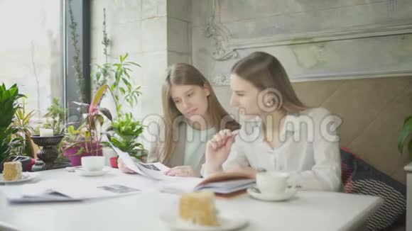 两个女商人在咖啡馆里讨论工作问题并翻阅文件视频的预览图