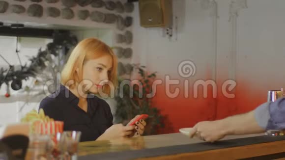 年轻的美女打手机喝咖啡酒吧背景视频的预览图