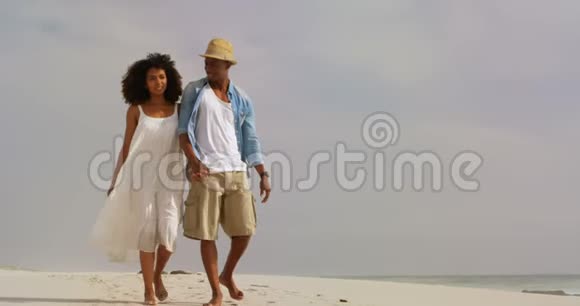 非裔美国人夫妇在海滩上手拉手散步的正面景色视频的预览图