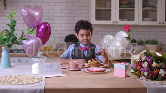 小可爱的男孩专心地在煎饼上浇糖浆视频的预览图