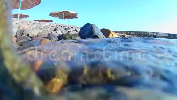 海浪卷到海滩上的岩石海岸上有着一把茅草伞你可以看到一个有红旗的码头在水下航行视频的预览图