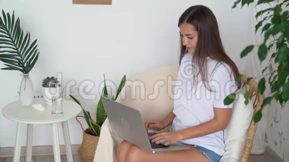 女自由职业者坐在稻草椅上在家里用笔记本电脑工作视频的预览图