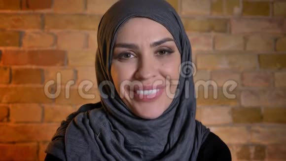 戴着头巾的穆斯林成年女性的特写镜头在舒适的室内开心地看着摄像机微笑视频的预览图