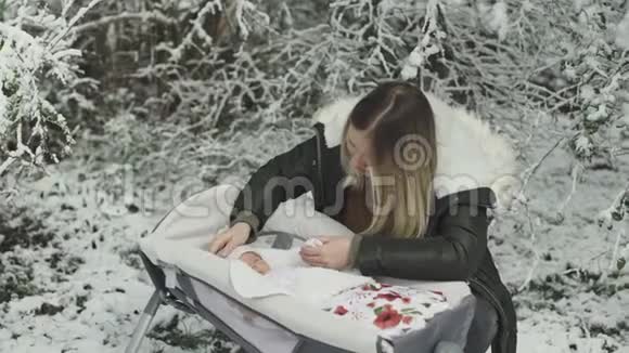 年轻时尚的妈妈和她可爱的女儿在冬天的雪公园视频的预览图