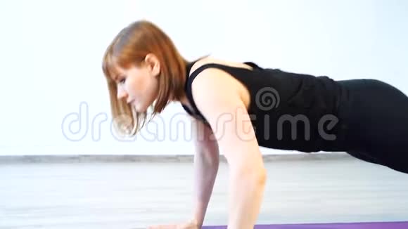 肌肉发达的年轻女人在运动垫上做俯卧撑视频的预览图