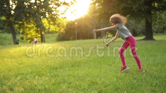 小女孩在绿色的草地上玩同时做一个杂技轮年轻的运动小子有一个非常好的心情视频的预览图