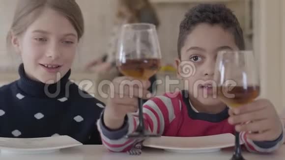 两个孩子坐在家里的桌子旁白人金发女孩和非裔美国男孩在一起玩得很开心那个男孩给了视频的预览图
