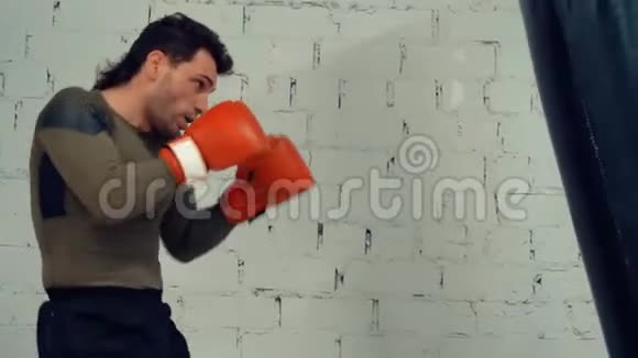 拳击手戴手套训练拳击手在白砖墙背景上踢球视频的预览图
