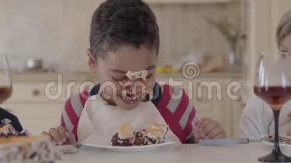 三个孩子坐在桌子旁玩得很开心男孩脸上涂着蛋糕两个白种人女孩和视频的预览图