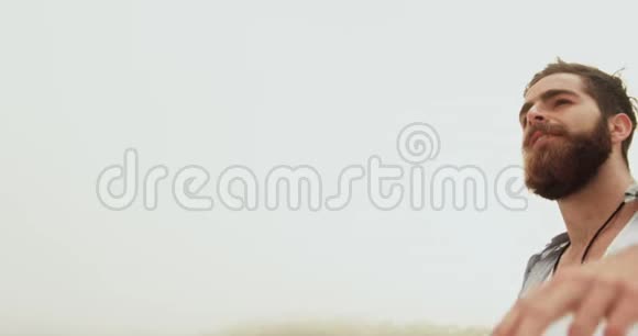 高加索男子伸臂站在沙滩上的侧视图4k视频的预览图
