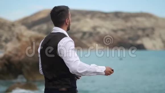 一个年轻英俊的男人在海边和山上扔石头在水里慢动作塞浦路斯帕福斯视频的预览图