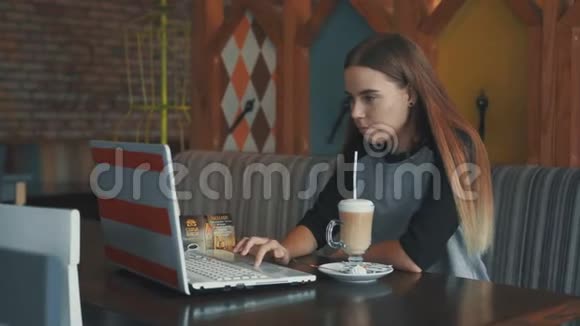 可爱的女孩在咖啡馆工作用笔记本电脑聊天在喝咖啡视频的预览图