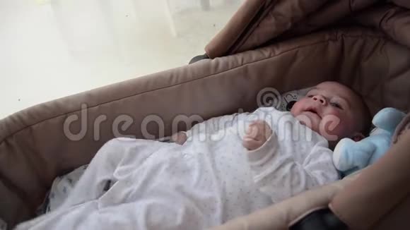 可爱的3个月大的男孩在婴儿床上做滑稽的表情视频的预览图
