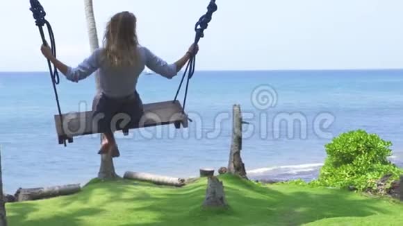 幸福的女人在蓝色的海洋景观上摇摆暑假期间无忧无虑的女孩在海滩上摇摆在夏天玩得开心视频的预览图