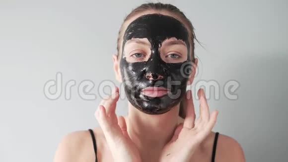 一位漂亮的年轻女子在脸上贴了一层黑色的面膜视频的预览图