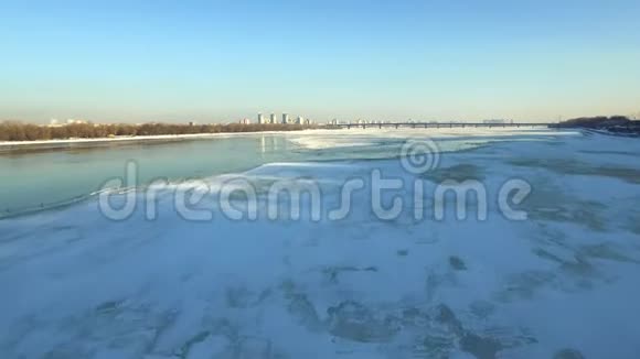 冬季城市冰冻河流的鸟瞰图鸟儿飞过冰河视频的预览图