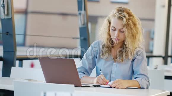 迷人的年轻女性在夏天的网站上工作使用笔记本电脑在笔记本上记笔记视频的预览图