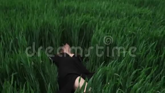 穿黑色衣服的女孩在草地上撒谎视频的预览图