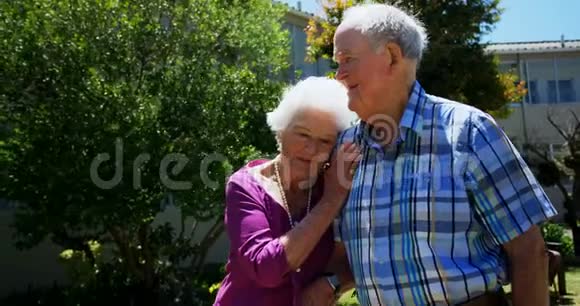 积极行动的高加索老年夫妇在养老院花园散步的正面景色视频的预览图