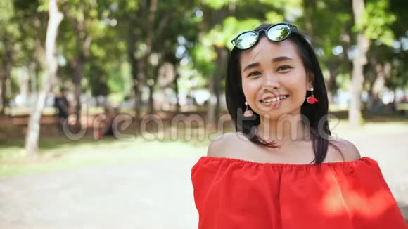 公园里一个穿红色衣服的年轻印度尼西亚女孩的肖像视频的预览图
