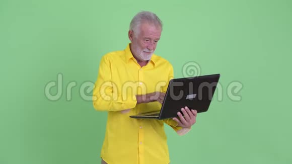 快乐的大胡子商人思考使用笔记本电脑视频的预览图