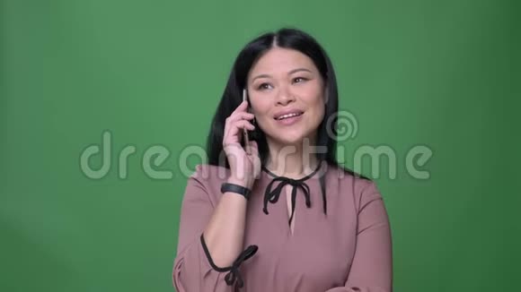 一位年轻迷人的黑发亚洲女性的特写镜头她在电话中交谈背景是孤立的视频的预览图