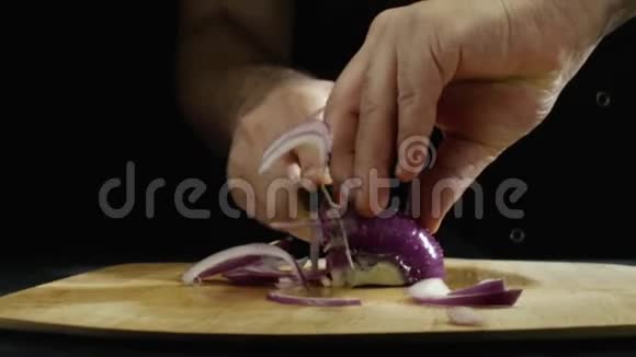 男人的特写他的手慢慢地拿着一个紫色的洋葱在餐厅厨房的木板上库存数据视频的预览图