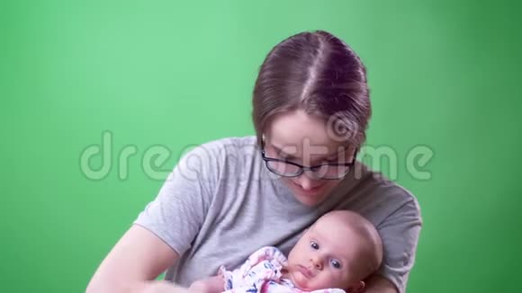 特写照片美丽的母亲摆姿势抱着她可爱和美丽的新生女儿在绿色背景视频的预览图