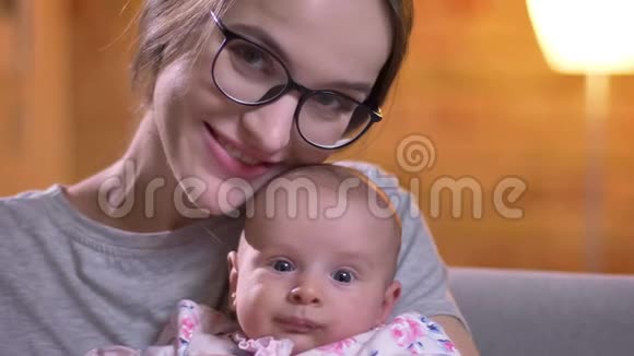 在客厅里妈妈和她可爱的刚出生的女儿拥抱在一起微笑地看着镜头的特写照片视频的预览图