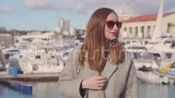 阳光明媚的春天成年的红发女子站在海港区视频的预览图