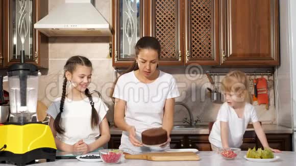 妈妈正和她的两个小女儿在厨房里烤蛋糕视频的预览图