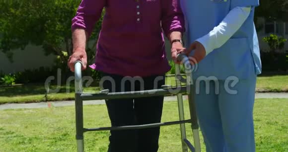 高加索女医生帮助老年患者与步行者在nu花园的正面景色视频的预览图