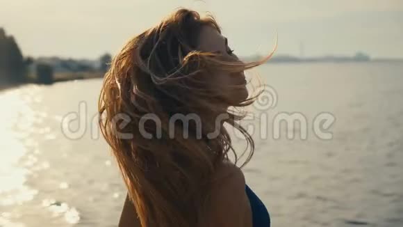 迷人的年轻女人的肖像长发比基尼在海滩上的日落时摆姿势视频的预览图