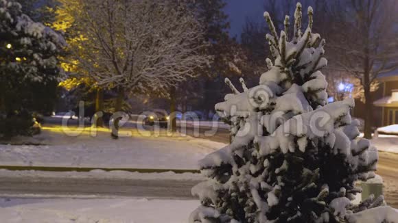 车灯在夜晚的冰路上在小区的雪落在房子上夜晚的冬天时间视频的预览图