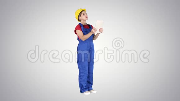 戴黄色安全帽的女工程师在检查建筑时正在看平板电脑视频的预览图