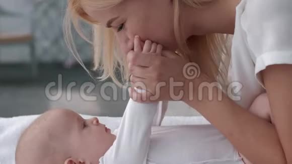母亲和孩子的关系父母亲吻她可爱的宝贝女儿的小手她躺在餐桌上紧紧地视频的预览图
