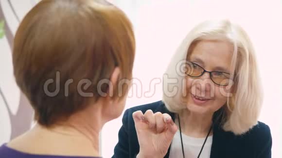 成熟的商务女性戴着眼镜与朋友亲密交谈视频的预览图