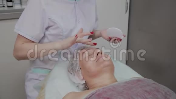 专业美容师对美容院的老年妇女使用保护霜视频的预览图