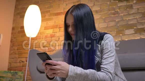 一位年轻迷人的白种人潮女的特写镜头她坐在电话里发短信并整理她的染发视频的预览图